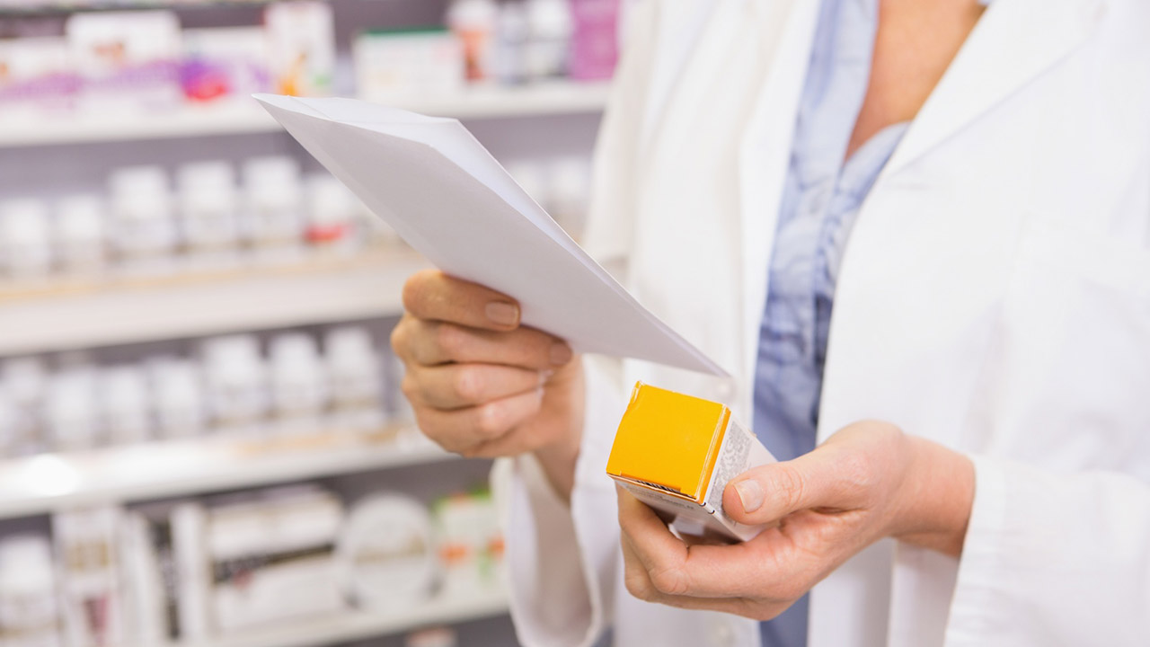 Pharmacist looks at prescription and medication